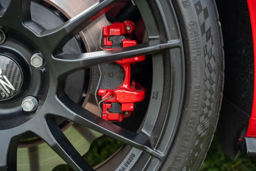 Red brake caliper behind a black wheel