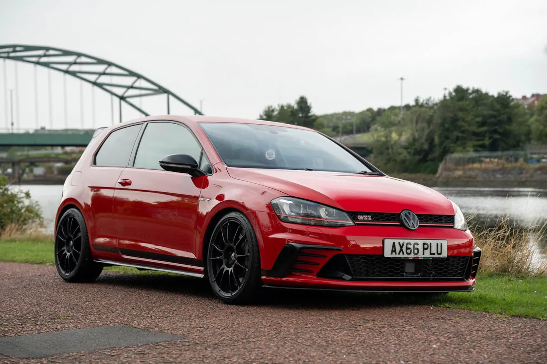 Red Golf GTI by a river bridge